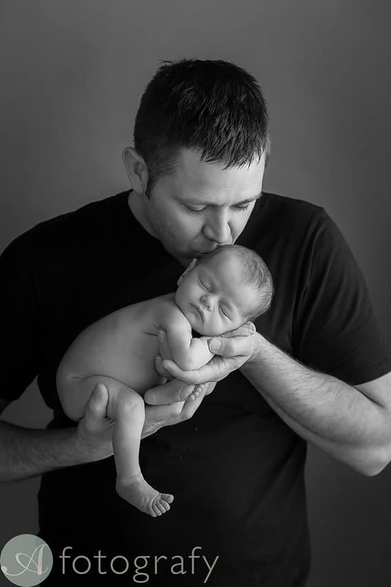 dad kissing newborn baby girl during photo session at Edinburgh studio
