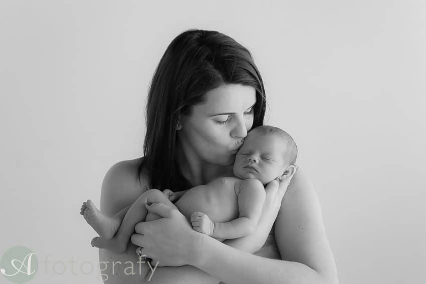 mum kissing baby during photo session. Black and white portrait.
