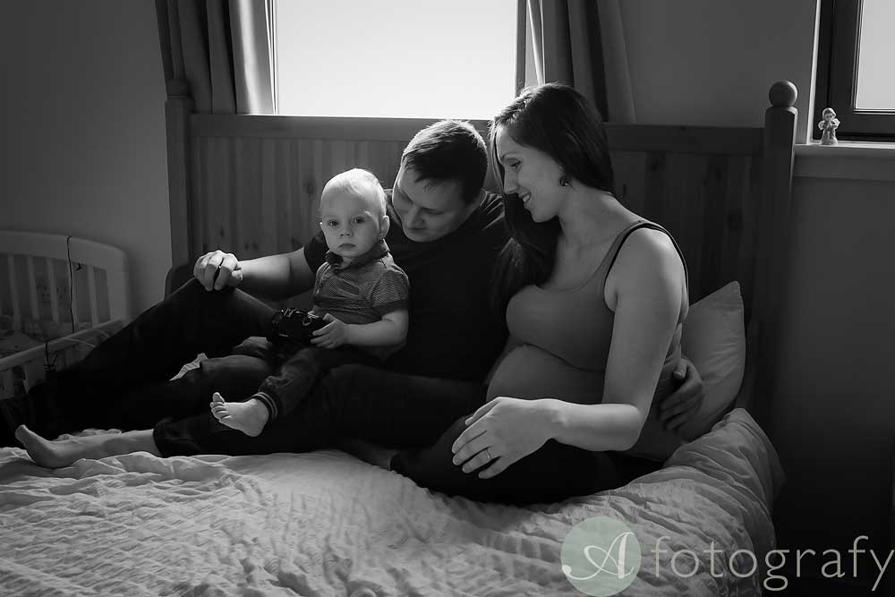 family sitting on bed during pregnancy session at home
