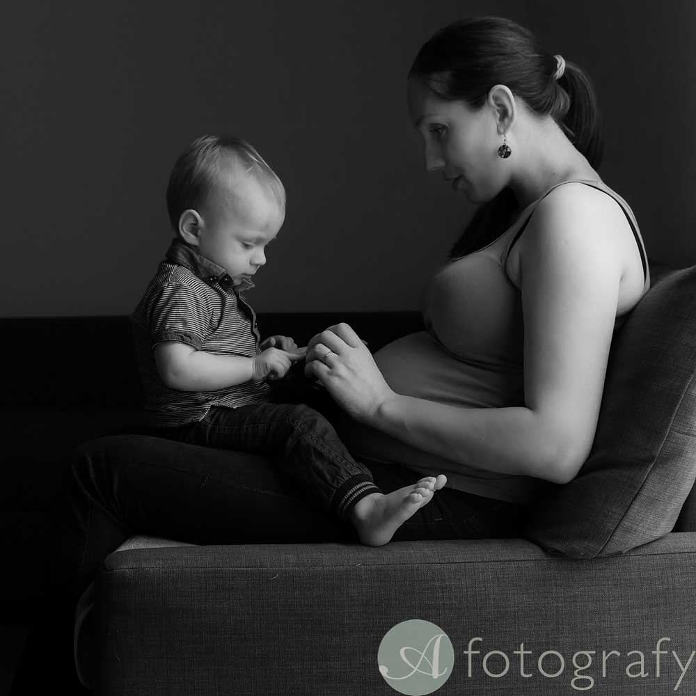 pregnant mum is sitting with toddler on lap during pregnancy photo session
