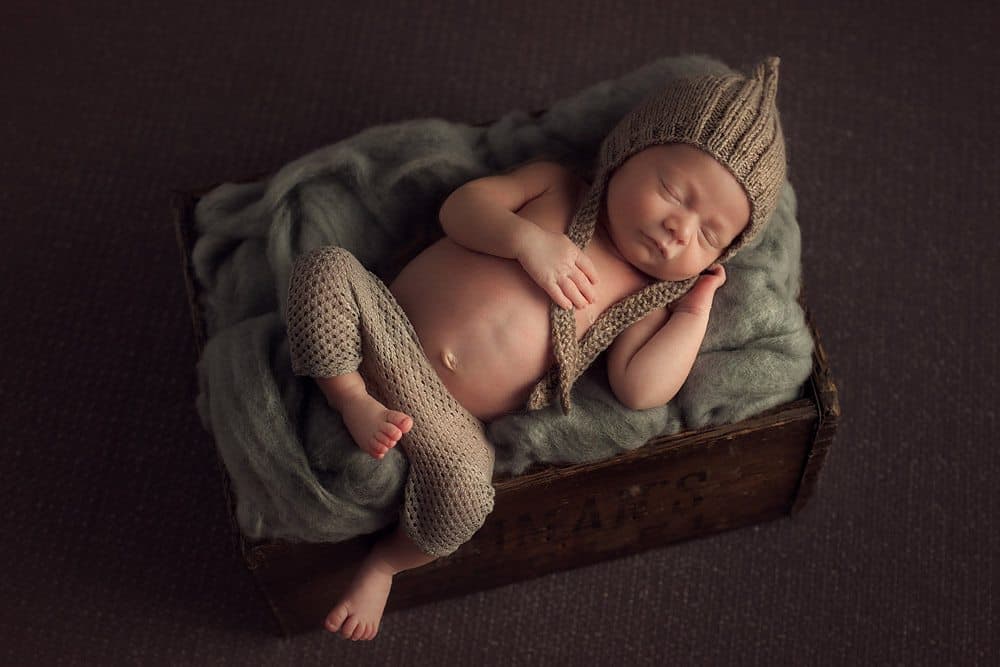 Newborn boy sleeping in box during photography session