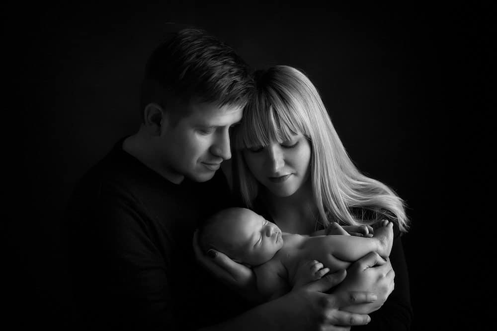Family holding newborn baby in black and white portrait