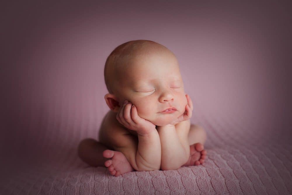 newborn creative posing froggy pose on pink background
