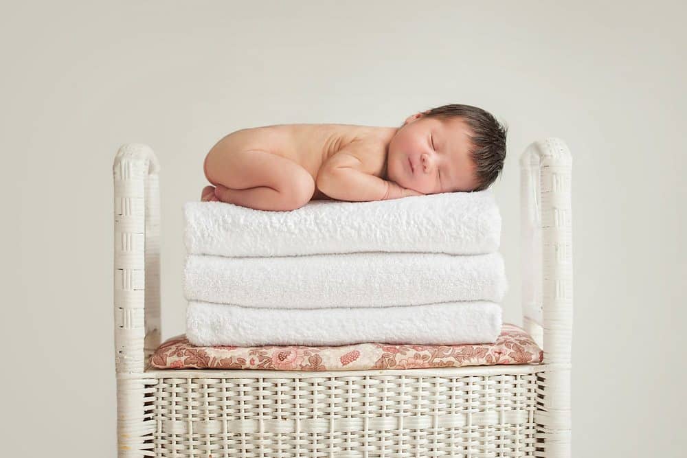 newborn baby girl on stack of towels