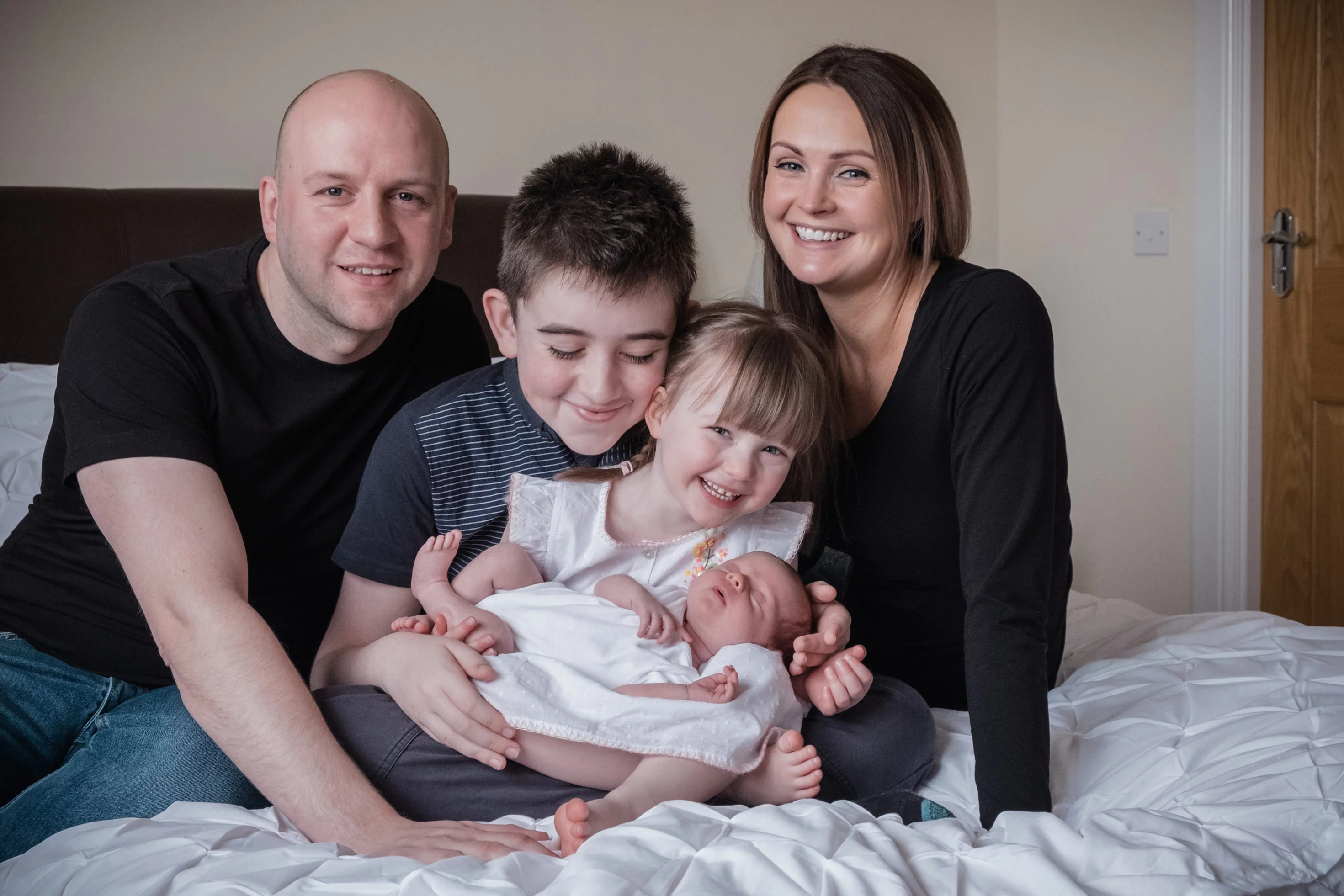 newborn photos at home with family posing on the bed