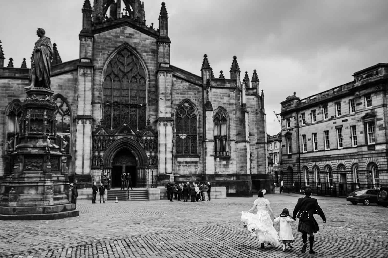 engaged couple running in front of St Giles Cathedral in Edinburgh. 
