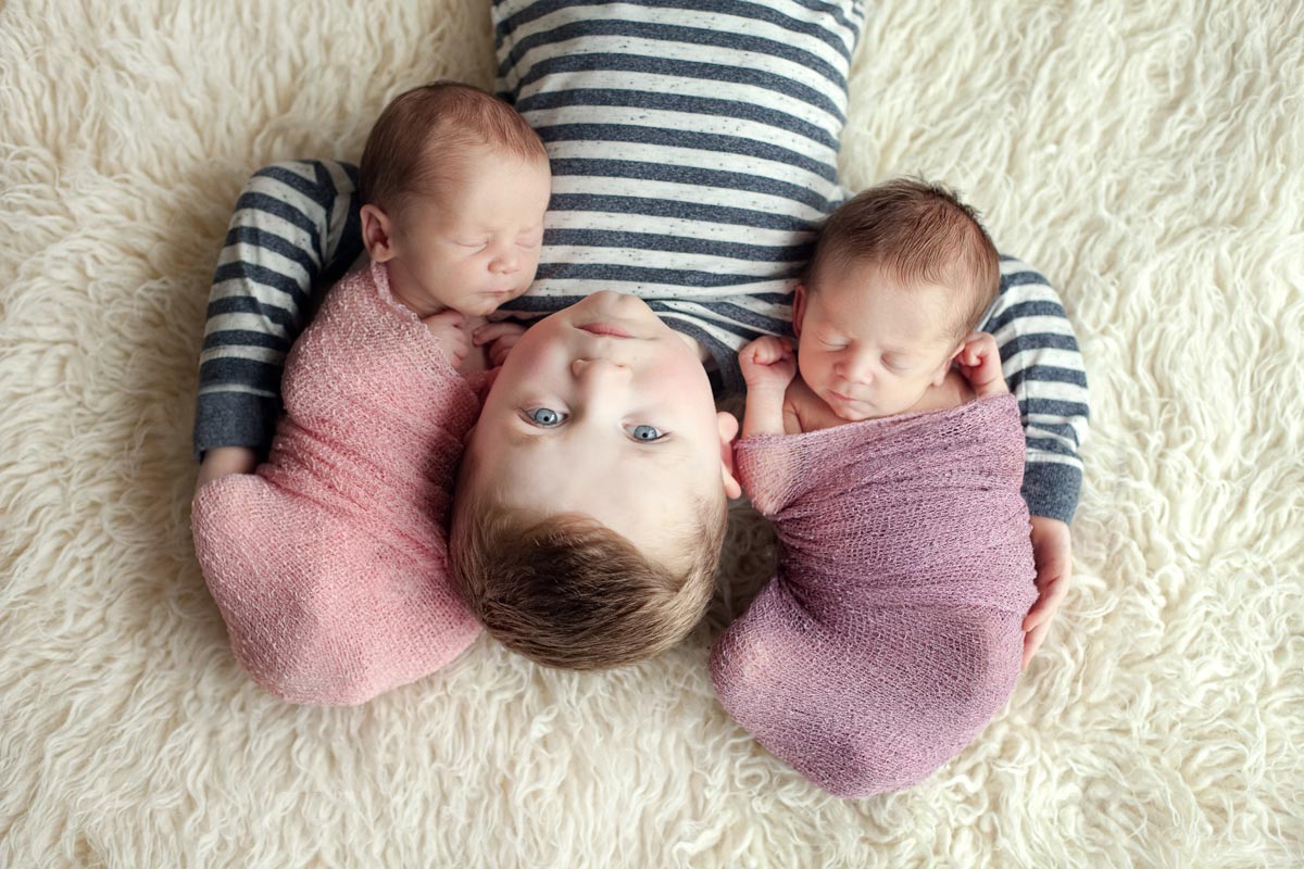 Toddler holding newborn twins babies