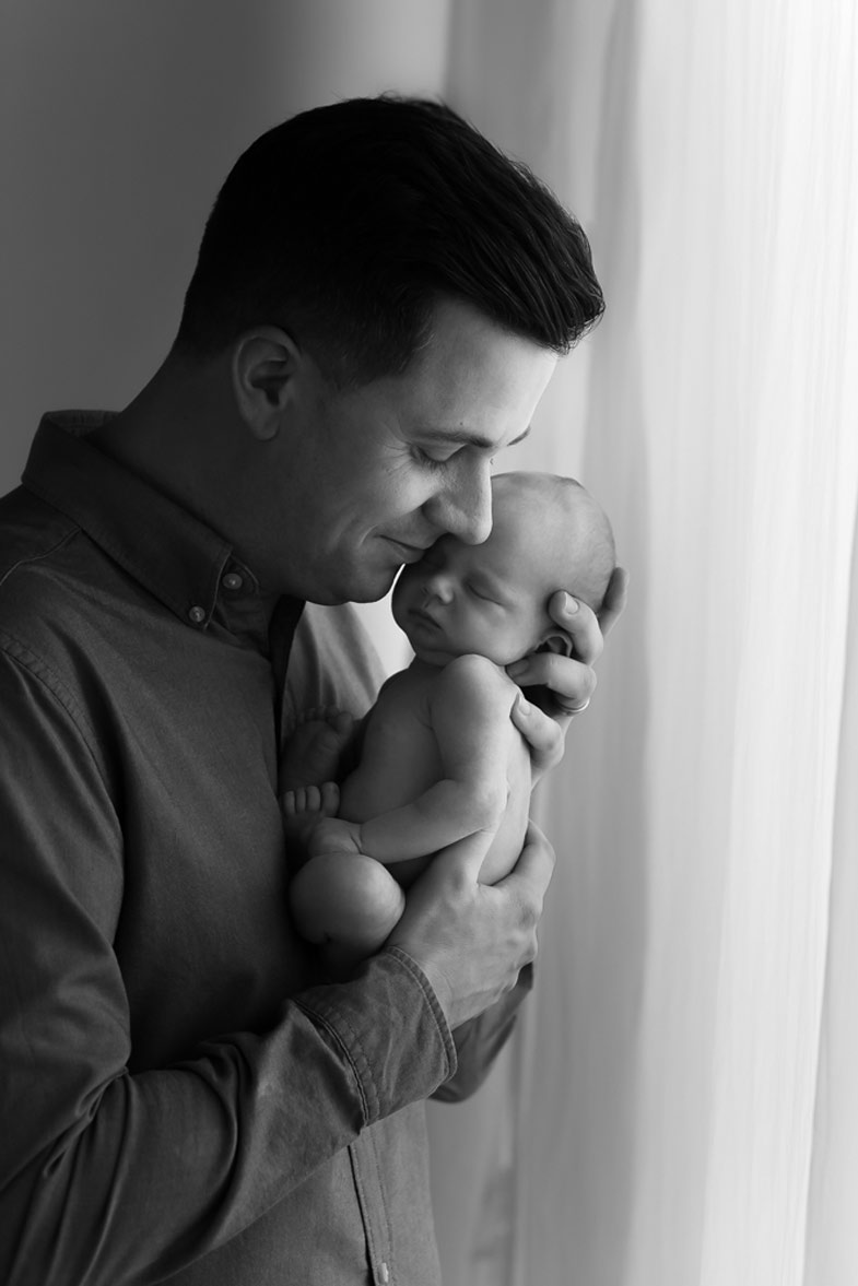dad is holding newborn baby during the photoshoot